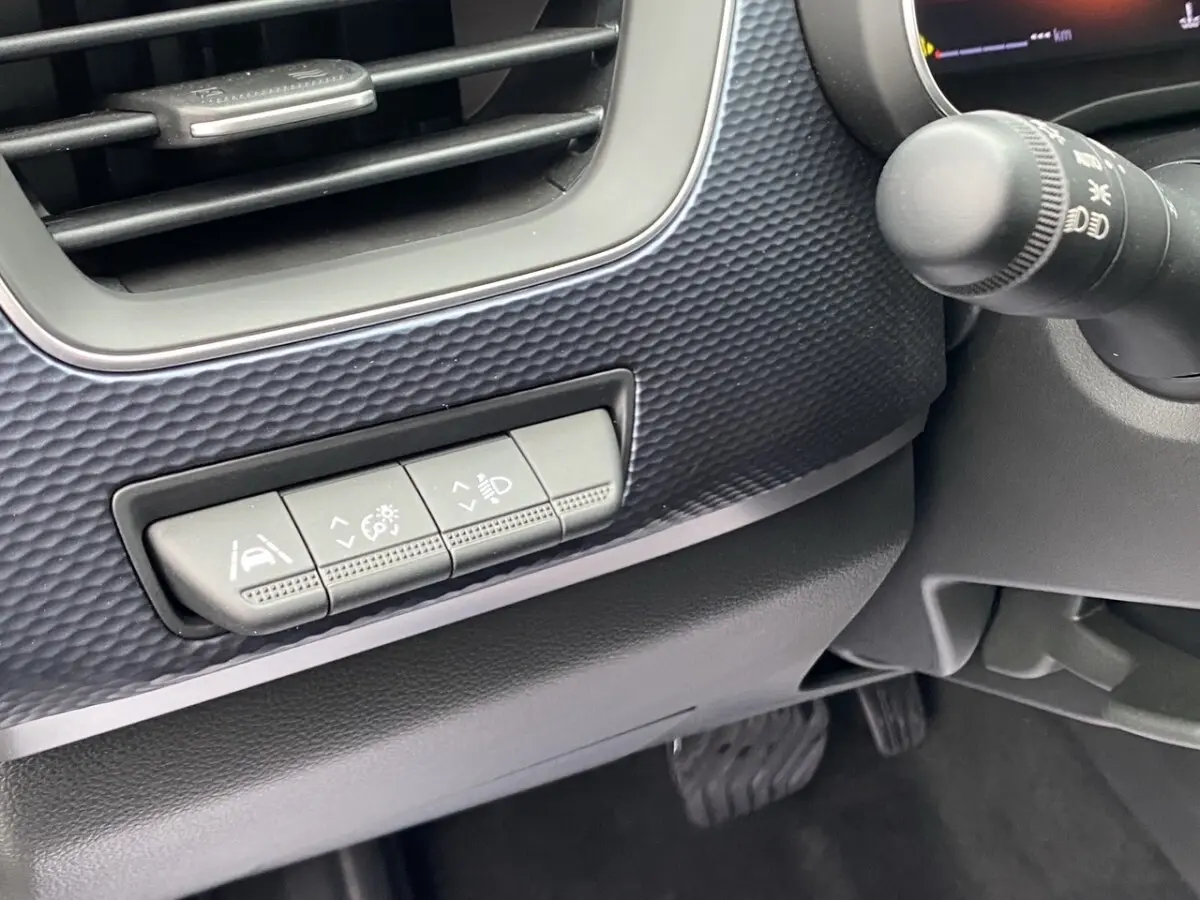Détail intérieur du tableau de bord noir du Renault Arkana PH2 Evolution, avec boutons de réglage d'assistance à la conduite.