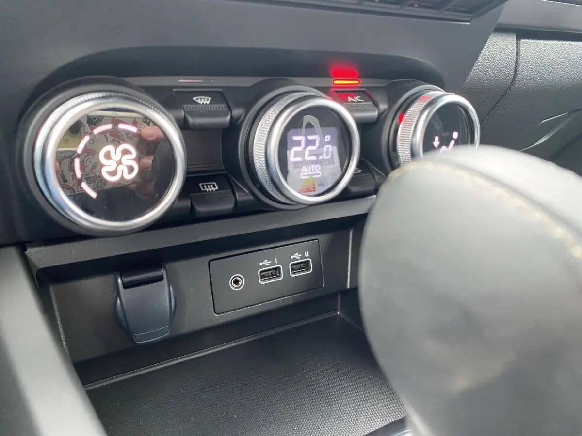 Détail des commandes de climatisation et ports USB du tableau de bord du Renault Arkana noir, vue intérieure rapprochée.