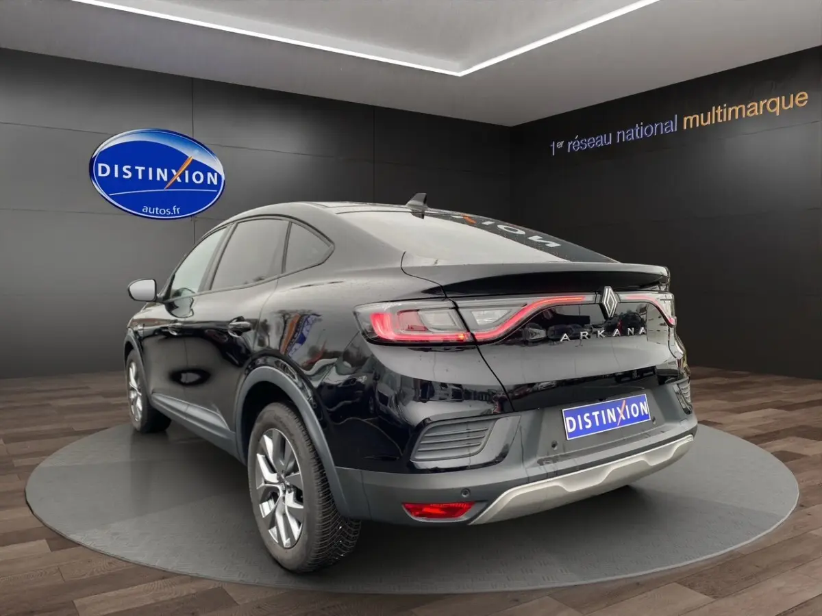 Vue 3/4 arrière droite du Renault Arkana noir 2024 avec feux LED et spoiler de coffre visible en showroom.