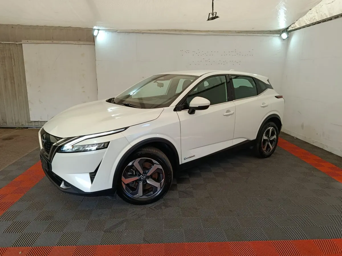 Vue 3/4 avant droit du Nissan Qashqai e-Power blanc avec jantes alliage et feux LED dans un espace fermé.