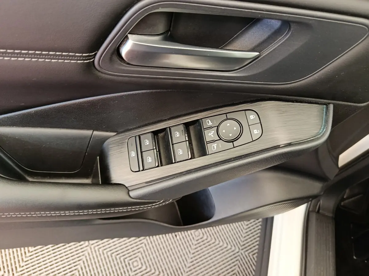 Vue rapprochée de la porte avant gauche du Nissan Qashqai blanc, avec commandes électriques des vitres et rétroviseurs.