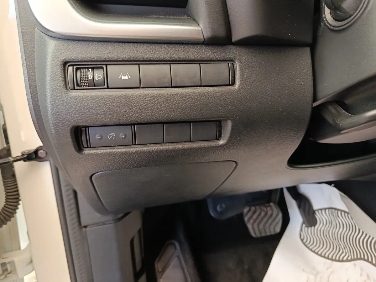 Vue rapprochée des commandes de réglage des phares et aide à la conduite côté gauche du tableau de bord noir du Nissan Qashqai blanc 2024.