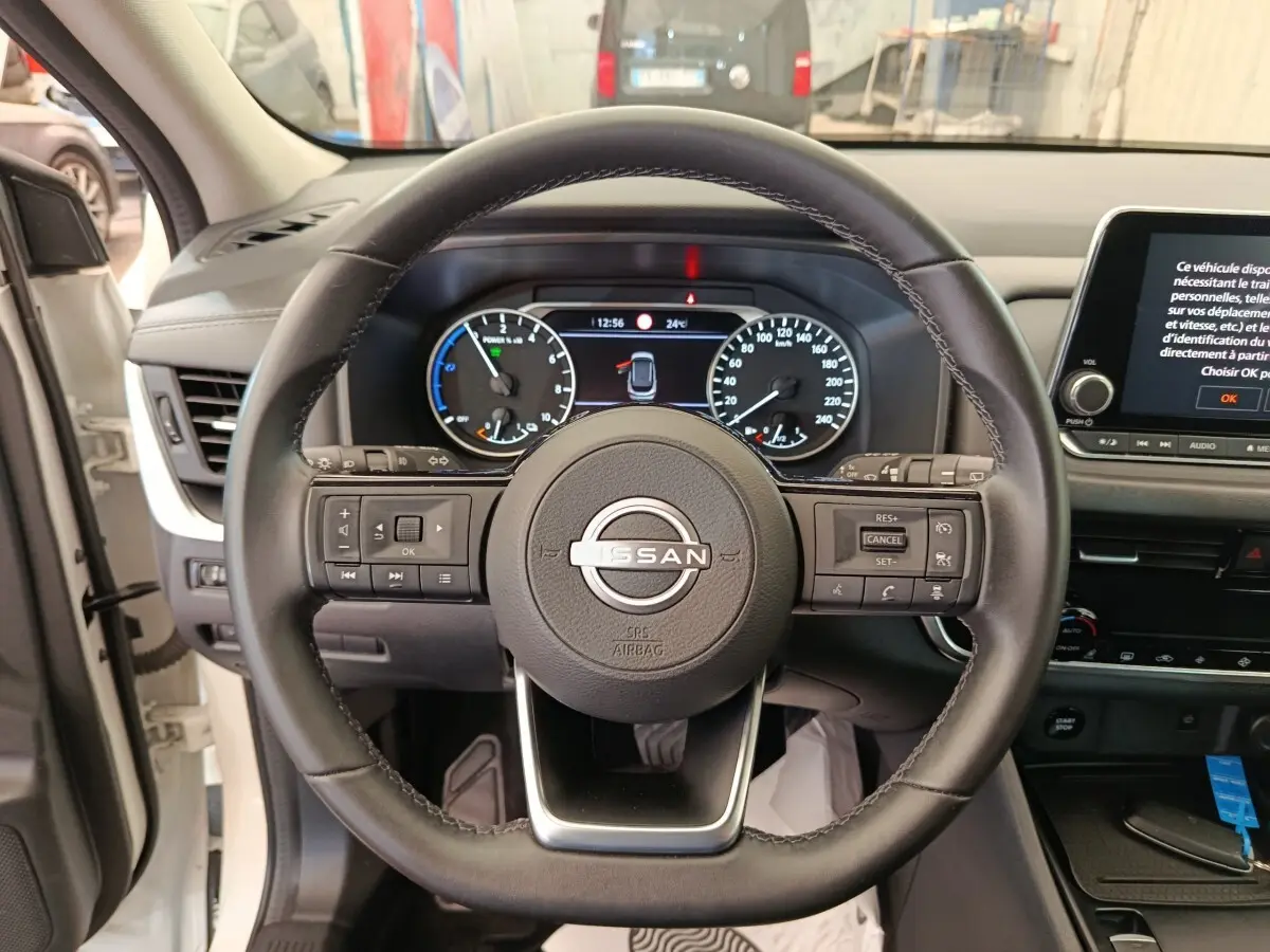 Vue frontale du volant en cuir noir du Nissan Qashqai e-Power 2024 avec tableau de bord digital et écran tactile central.