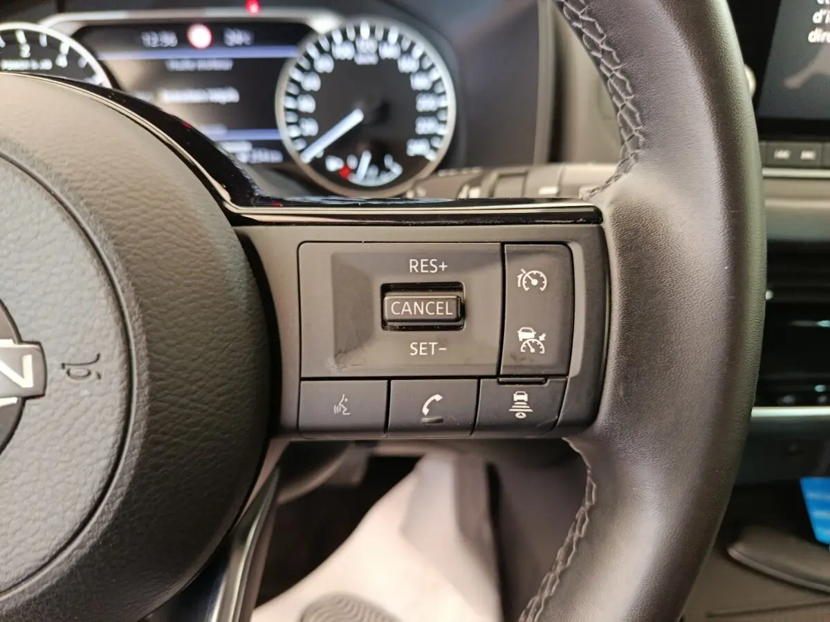 Gros plan sur les commandes du régulateur de vitesse au volant cuir noir du Nissan Qashqai e-Power 2024.