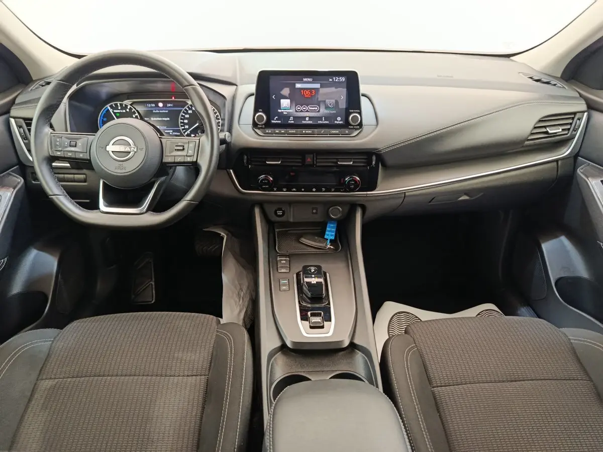 Vue intérieure avant du Nissan Qashqai e-Power 190 Business Edition 2024, tableau de bord et volant noir avec écran tactile central.