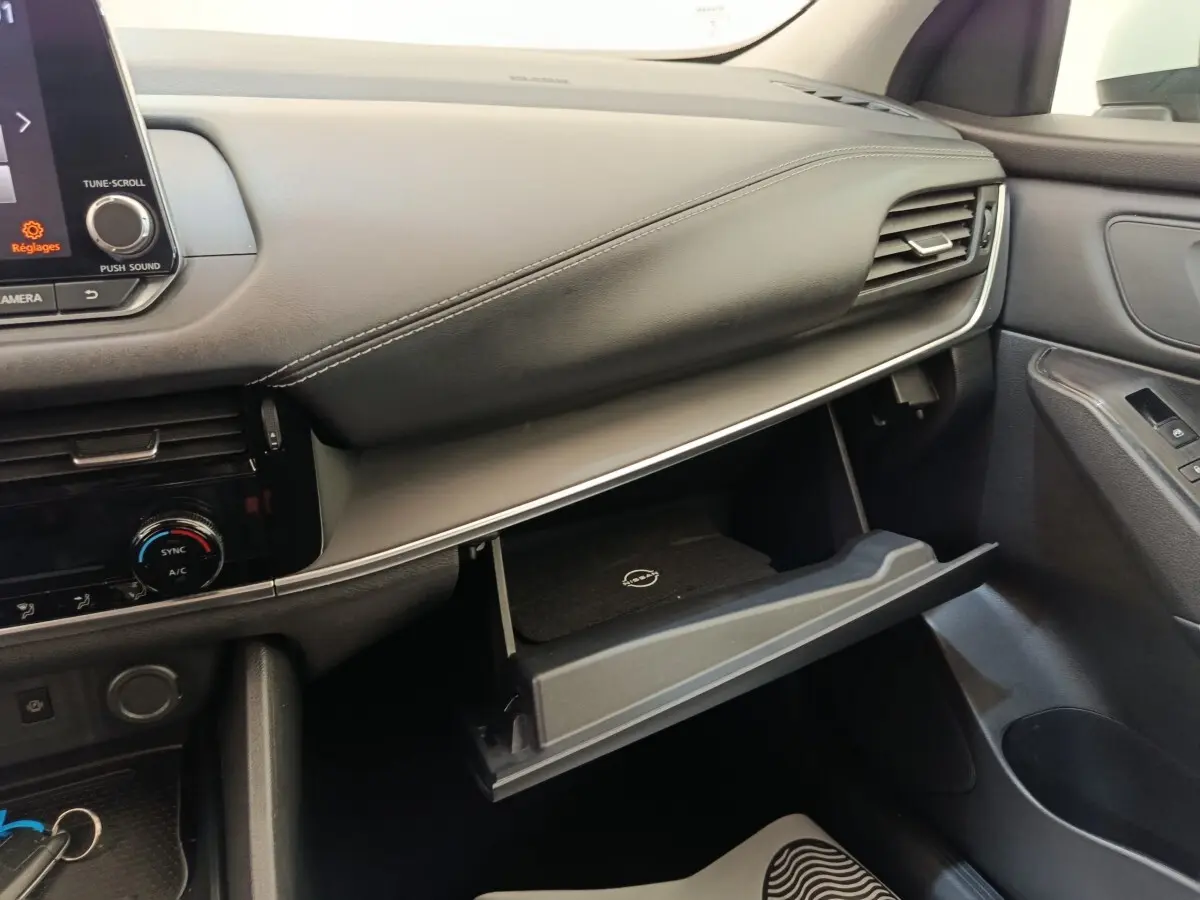 Intérieur côté passager du Nissan Qashqai e-Power 2024, tableau de bord gris avec boîte à gants ouverte.