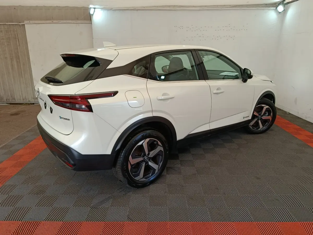 Vue 3/4 arrière droite du Nissan Qashqai e-Power blanc avec jantes alliage et toit noir dans un garage.