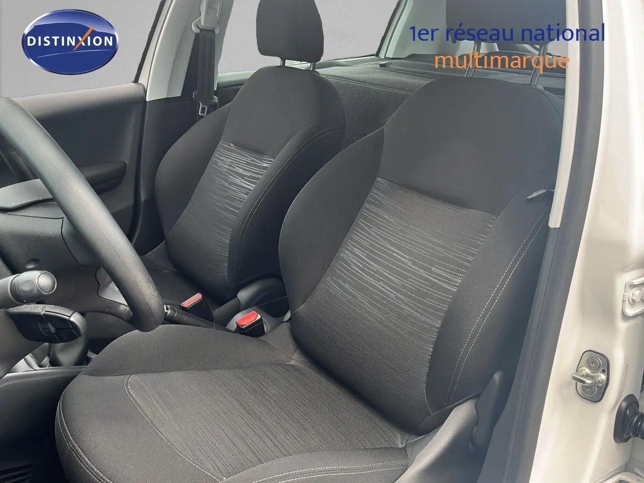 Intérieur de la Peugeot 208 blanche, vue côté conducteur, mettant en valeur les sièges noirs en tissu.