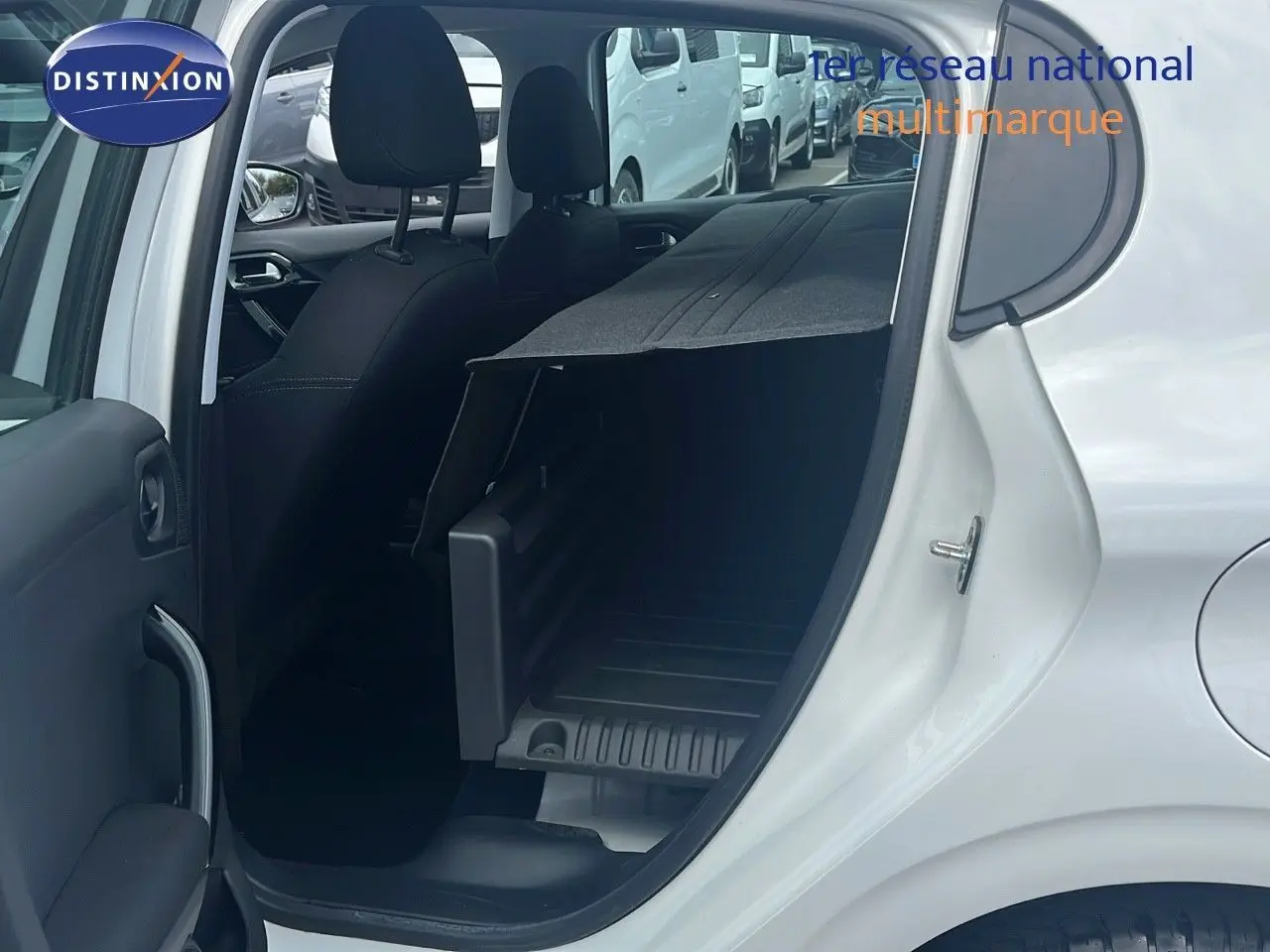 Vue côté gauche arrière d'une Peugeot 208 blanche banquise 2020 avec siège arrière rabattable et coffre aménagé.