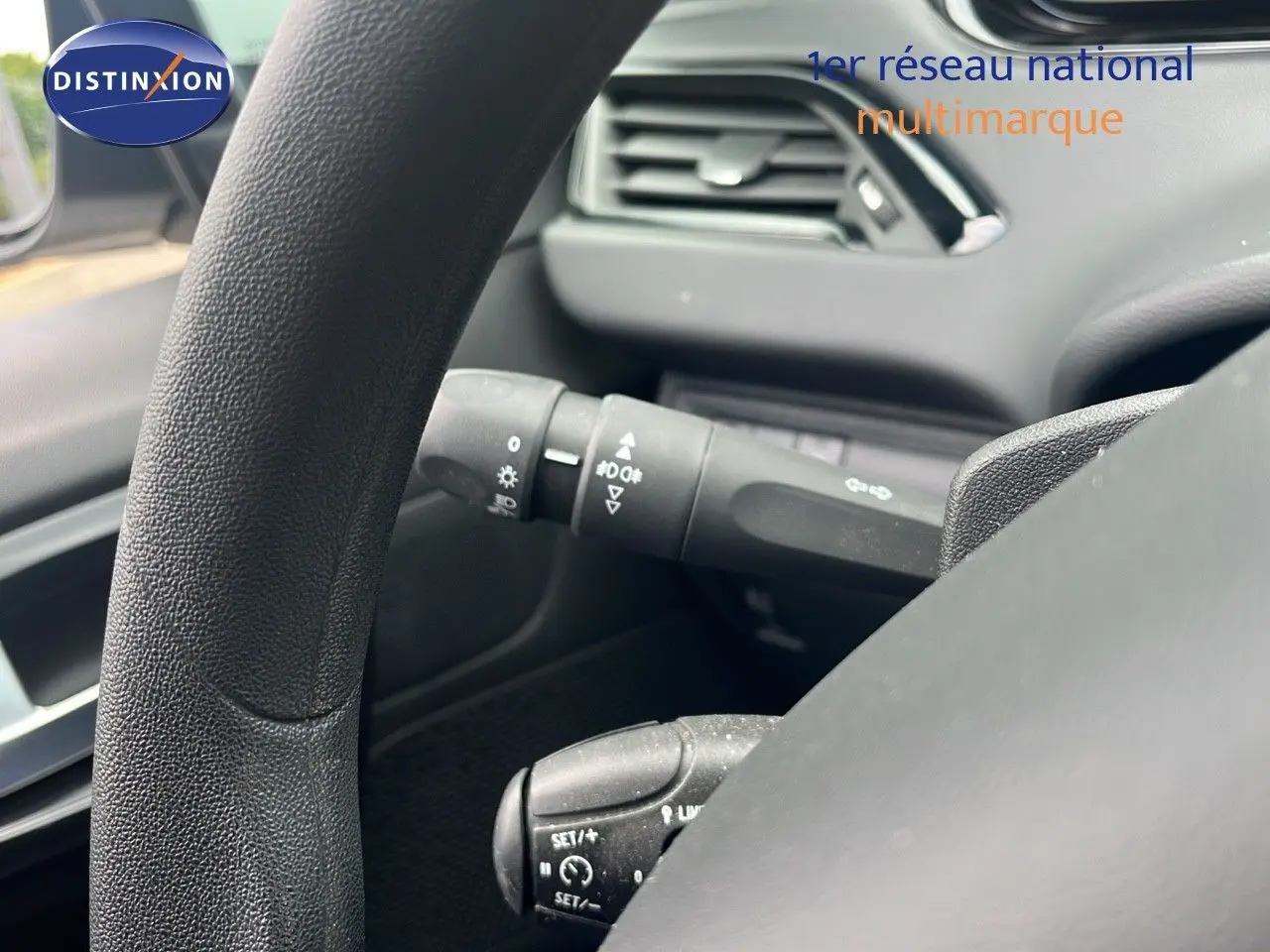 Gros plan sur le volant et les commandes au volant d'une Peugeot 208 blanche, version Société 2020, intérieur noir.
