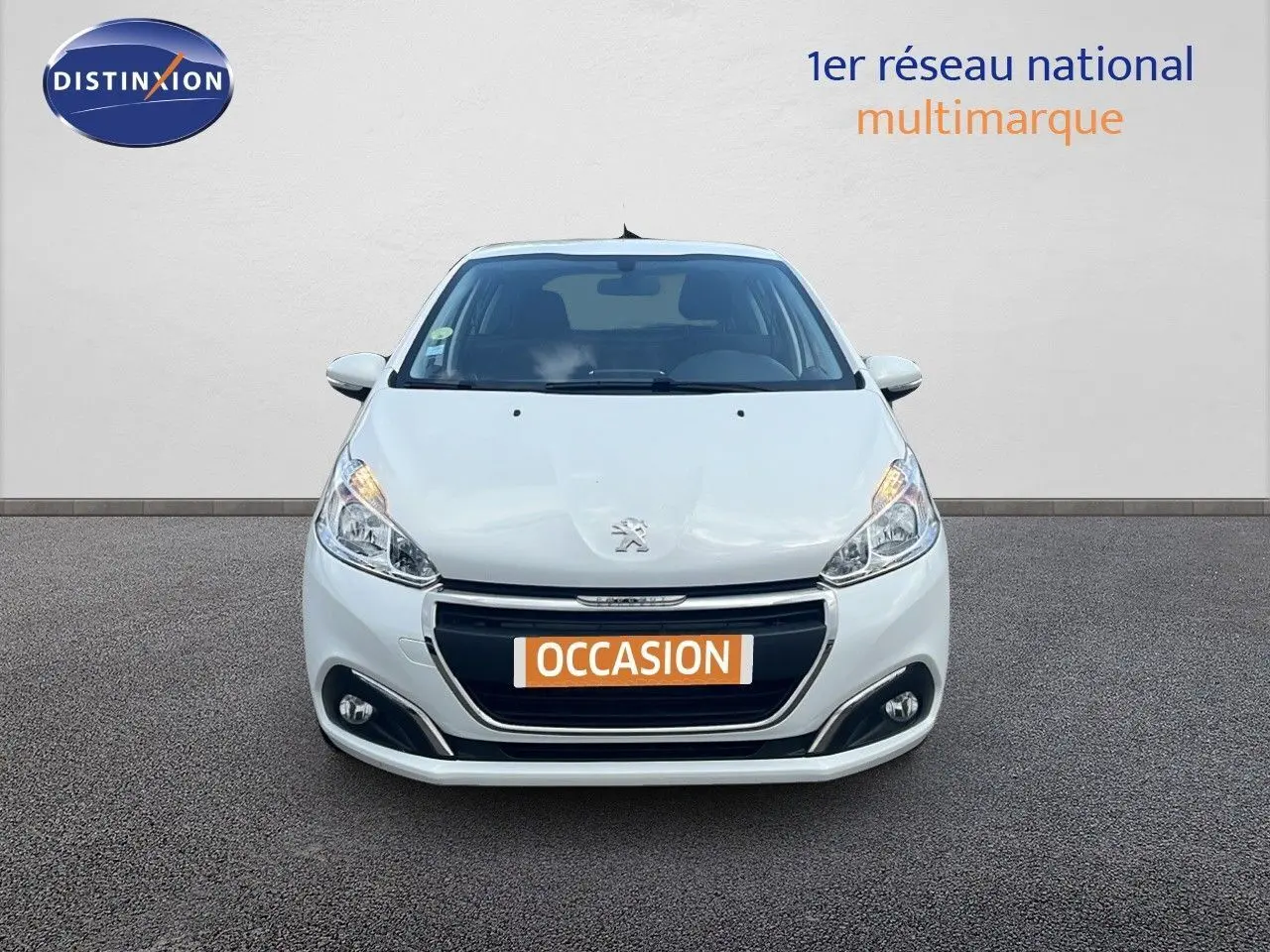 Peugeot 208 blanc banquise vue de face, mettant en valeur sa calandre et ses phares allumés.