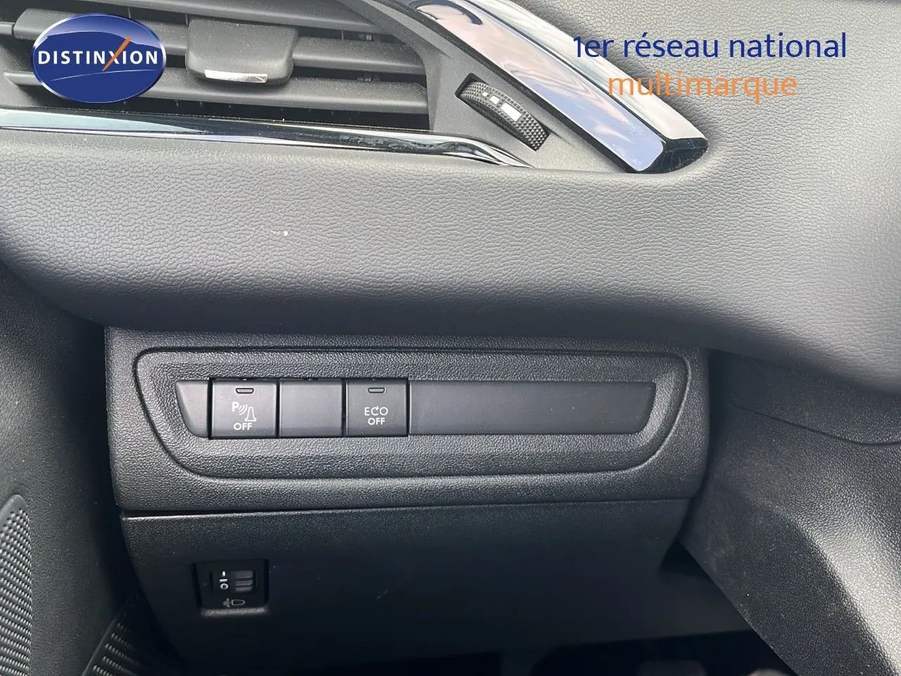 Détail intérieur côté gauche du tableau de bord de la Peugeot 208 blanche montrant les boutons ECO et parking.