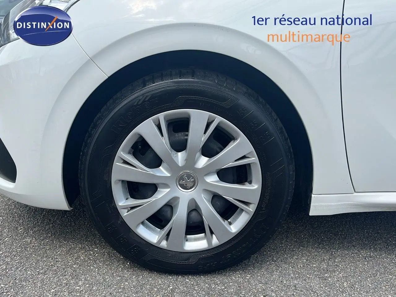 Gros plan sur la roue avant gauche blanche d'une Peugeot 208 Societe 2020 avec enjoliveur argenté et logo lion central.