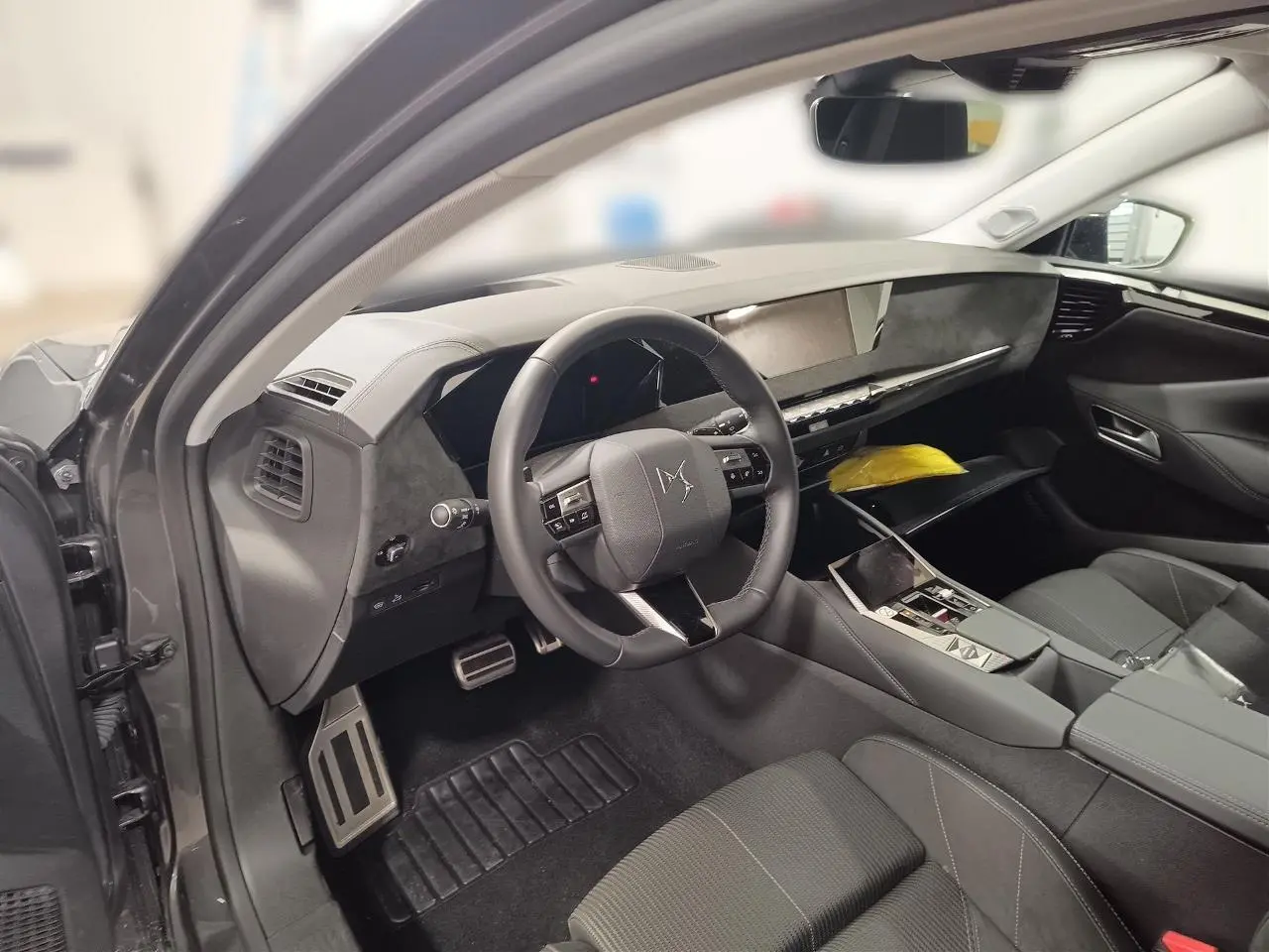 Intérieur avant gauche du DS4 2025 gris Platinium, volant cuir, planche de bord élégante et sièges tissu Alcantara.