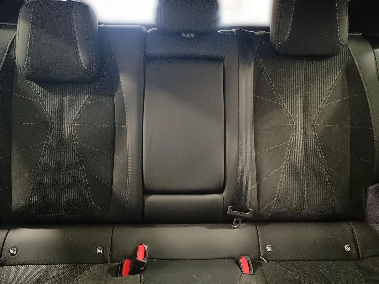 Vue intérieure des sièges arrière en tissu tressé noir avec alcantara du DS4 2025, accoudoir central relevé.