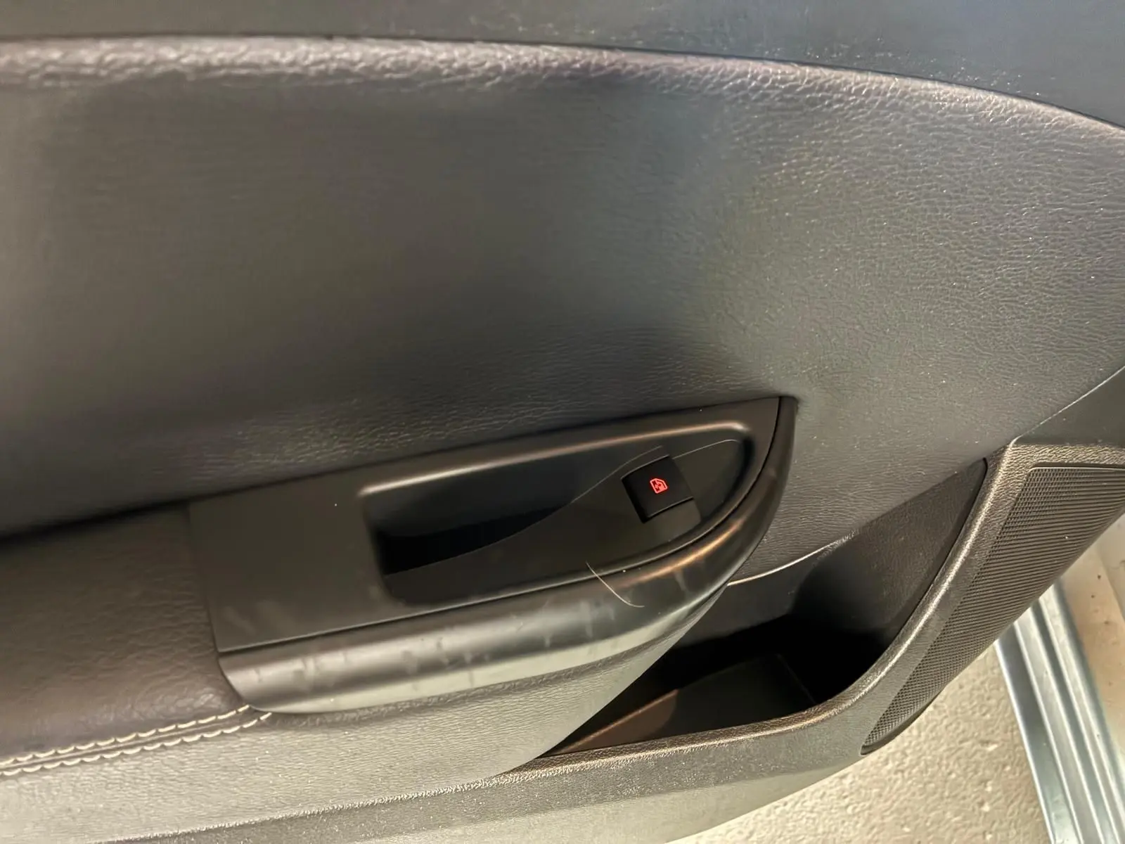 Détail de la poignée intérieure de porte côté gauche d’une Opel Astra gris 2015 avec bouton de verrouillage électrique.