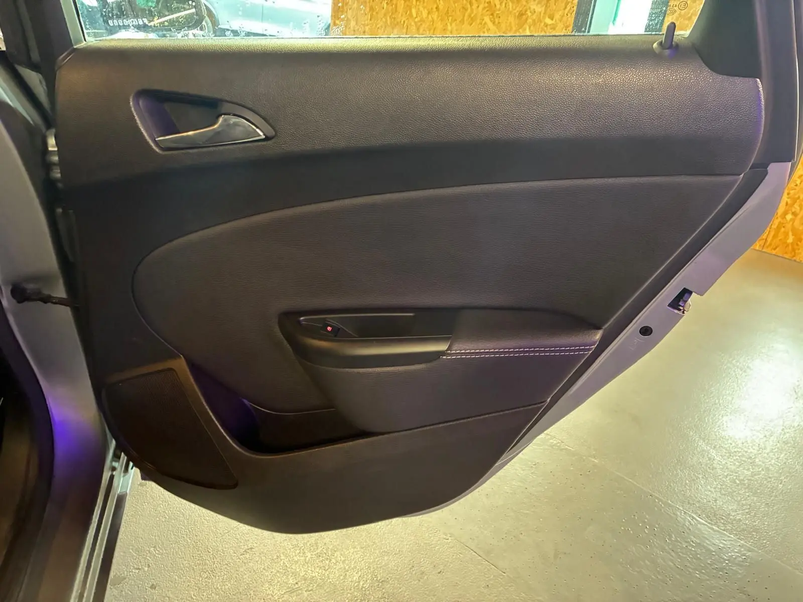 Vue rapprochée de la porte arrière gauche noire de l’Opel Astra 1.6 CDTI 110 gris, avec poignée intérieure et haut-parleur intégré.