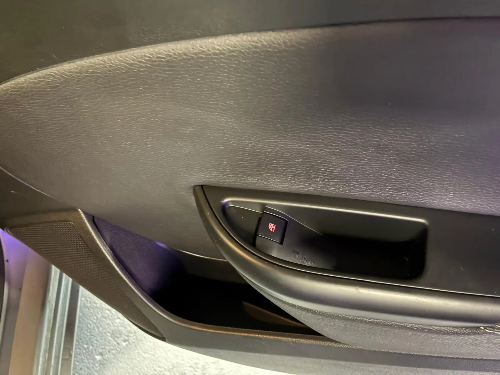 Gros plan sur la commande de lève-vitre côté gauche de la porte intérieure d’une Opel Astra gris 2015.