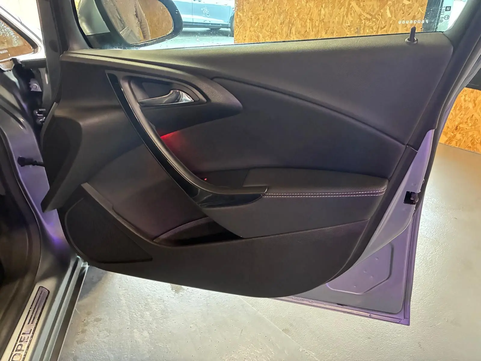 Vue intérieure de la porte côté gauche d'une Opel Astra gris 2015, avec garniture noire et surpiqûres blanches.