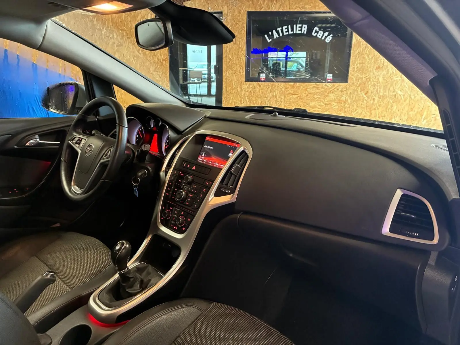 Vue intérieure côté conducteur de l’Opel Astra gris 2015, avec tableau de bord et console centrale rétroéclairée.