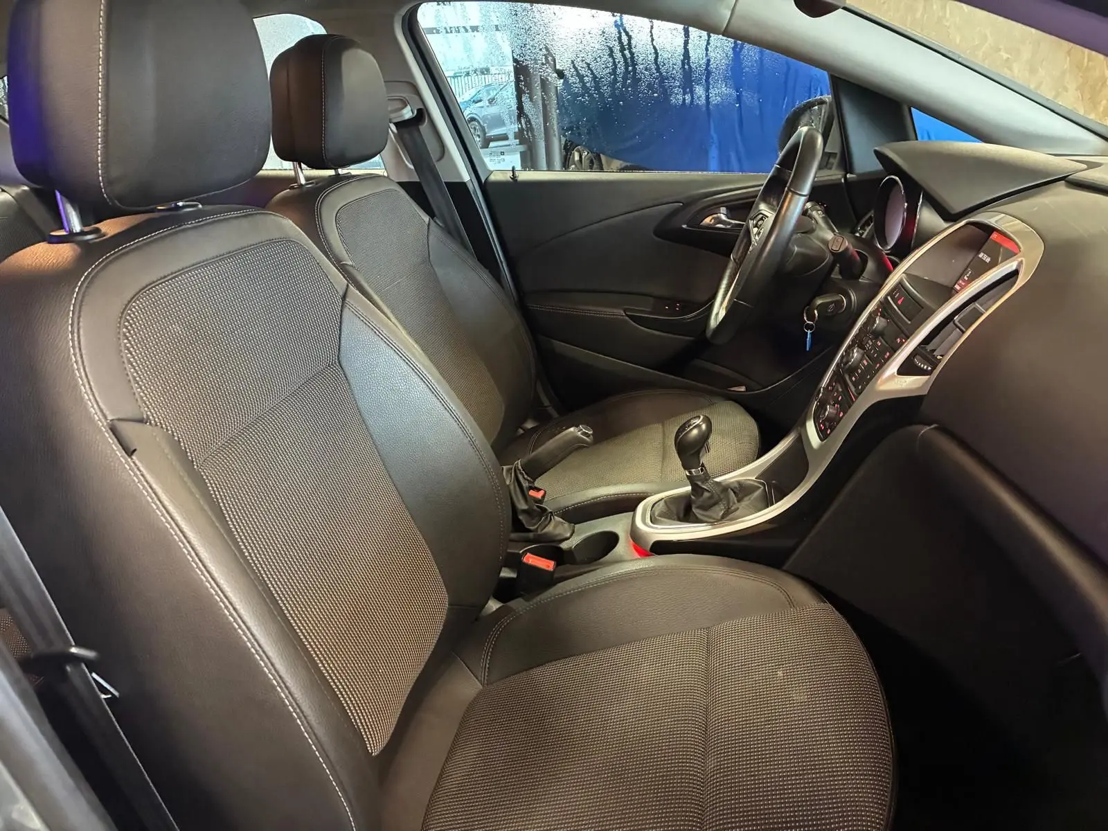 Intérieur avant droit de l’Opel Astra gris 2015, montrant les sièges, volant et console centrale avec boîte manuelle.