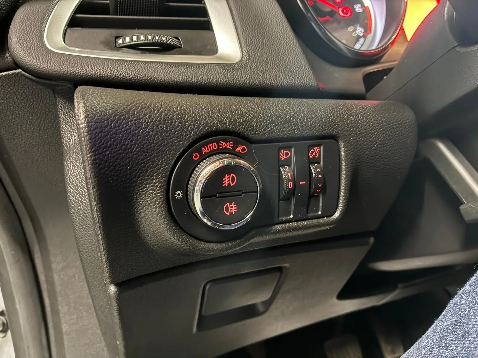 Gros plan sur le tableau de bord côté gauche de l'Opel Astra gris, montrant les commandes d'éclairage avec voyants rouges.