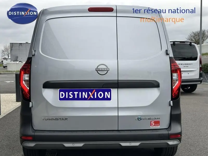 Vue arrière d'un Nissan Townstar électrique gris 2024 avec double portes arrière fermées et logo Zero Emission visible.