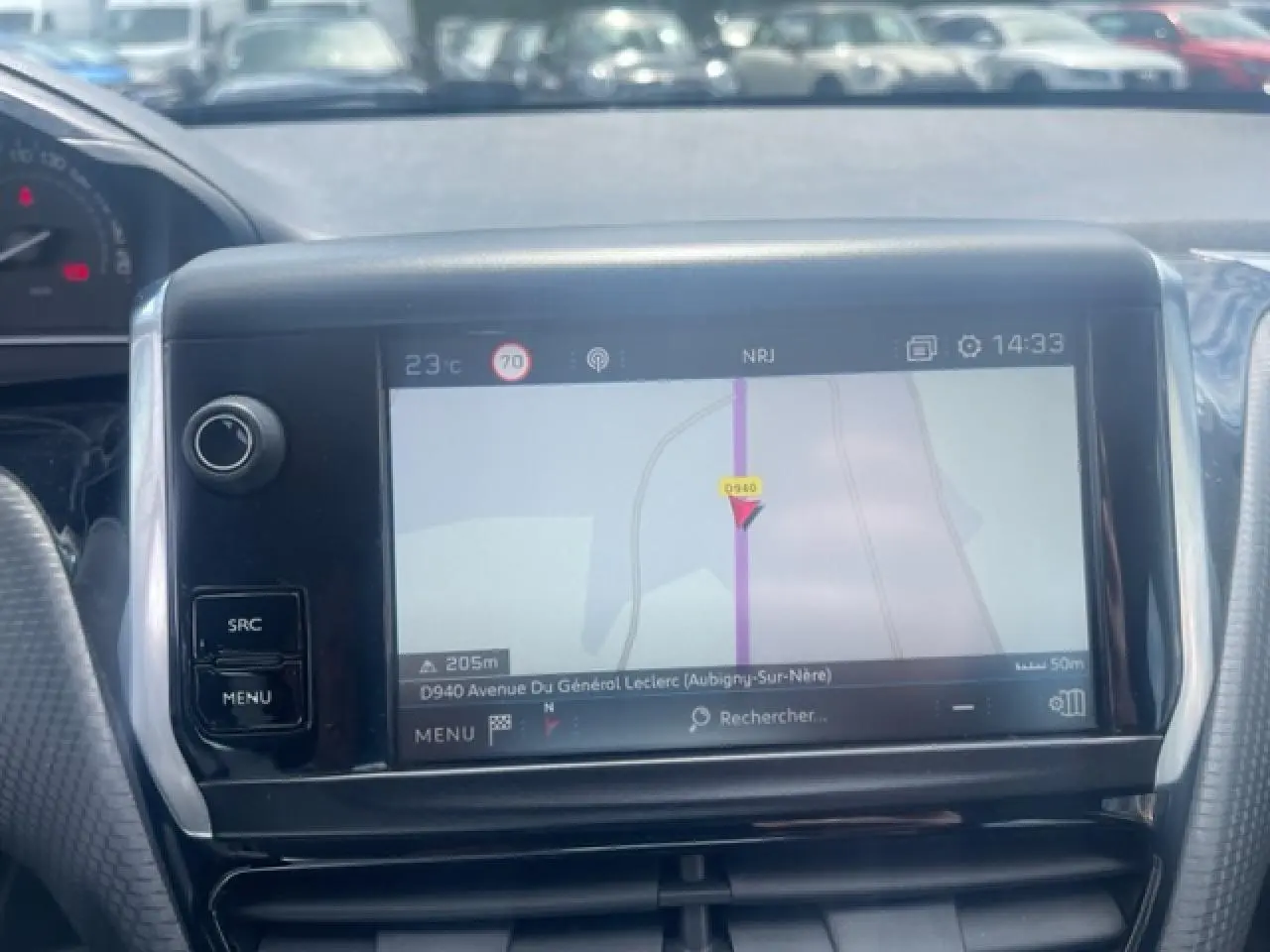 Écran tactile de navigation 3D au tableau de bord d'une Peugeot 208 blanche perle, vue intérieure frontale.