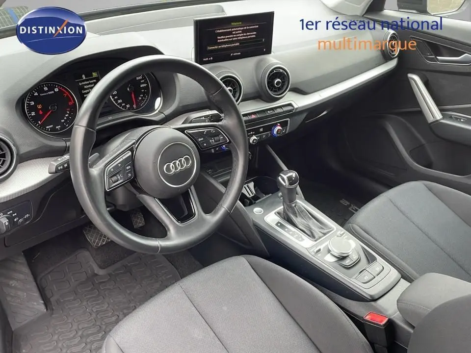 Intérieur noir de l'Audi Q2 35 TFSI 2023 vu côté conducteur, avec volant multifonction et console centrale moderne.