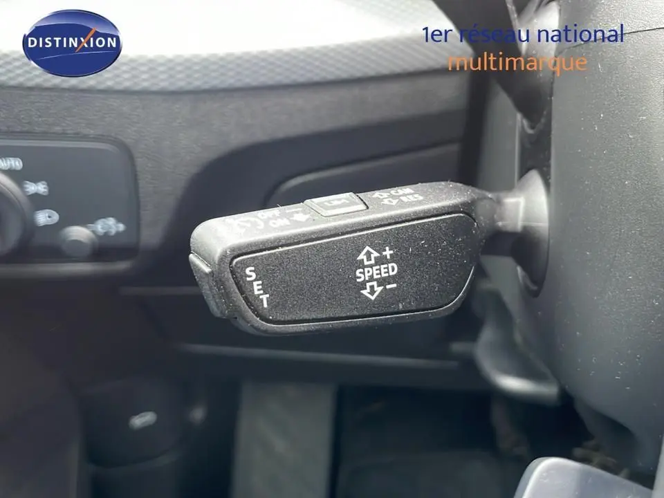 Gros plan sur la commande de régulateur de vitesse à gauche du volant dans l'Audi Q2 noir mito metal 2023.