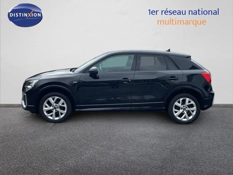 Profil latéral droit d'un Audi Q2 35 TFSI S-Line noir mito metal avec jantes alliage et vitres teintées, sur fond neutre.