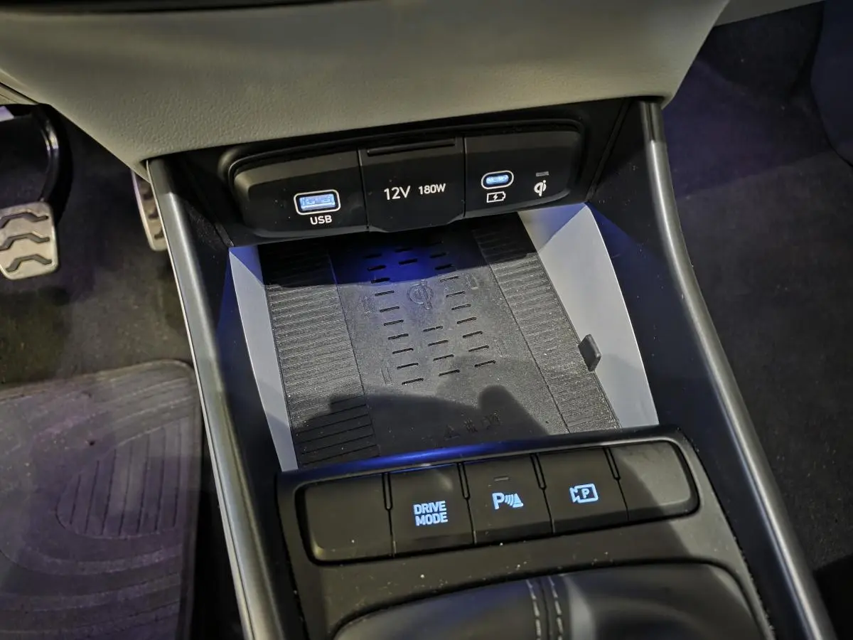 Gros plan sur la console centrale noire du Hyundai Bayon 2025, avec chargeur sans fil et commandes de stationnement.
