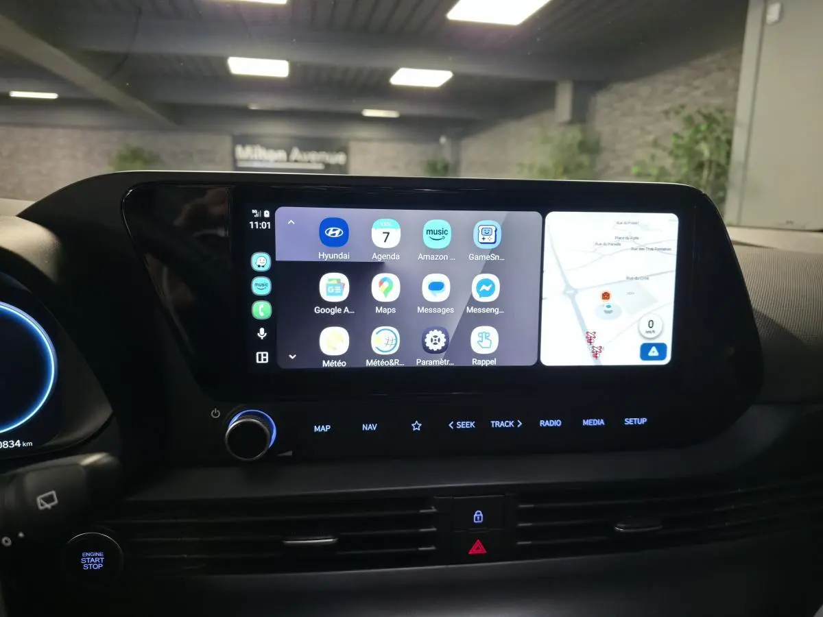 Vue rapprochée de l'écran tactile central du tableau de bord de la Hyundai Bayon noire avec interface connectée et commandes lumineuses.