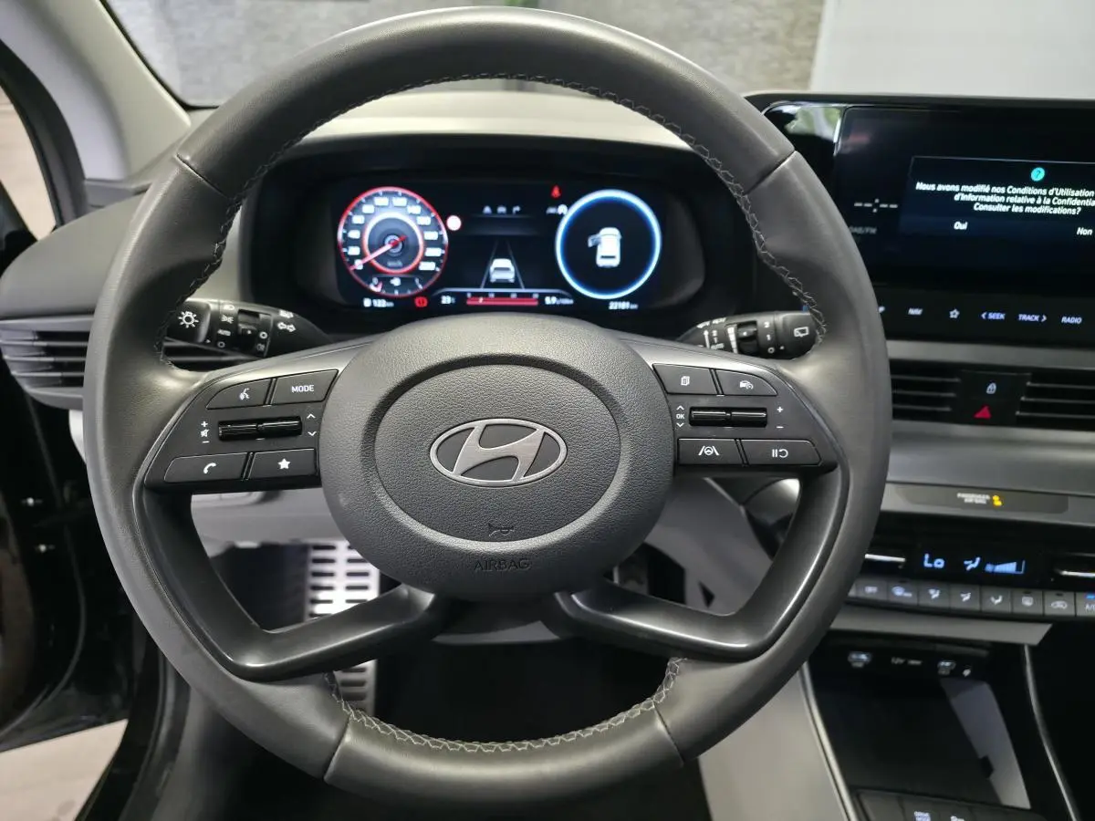 Vue rapprochée du volant cuir noir de la Hyundai Bayon 2025 avec tableau de bord numérique et écran tactile.