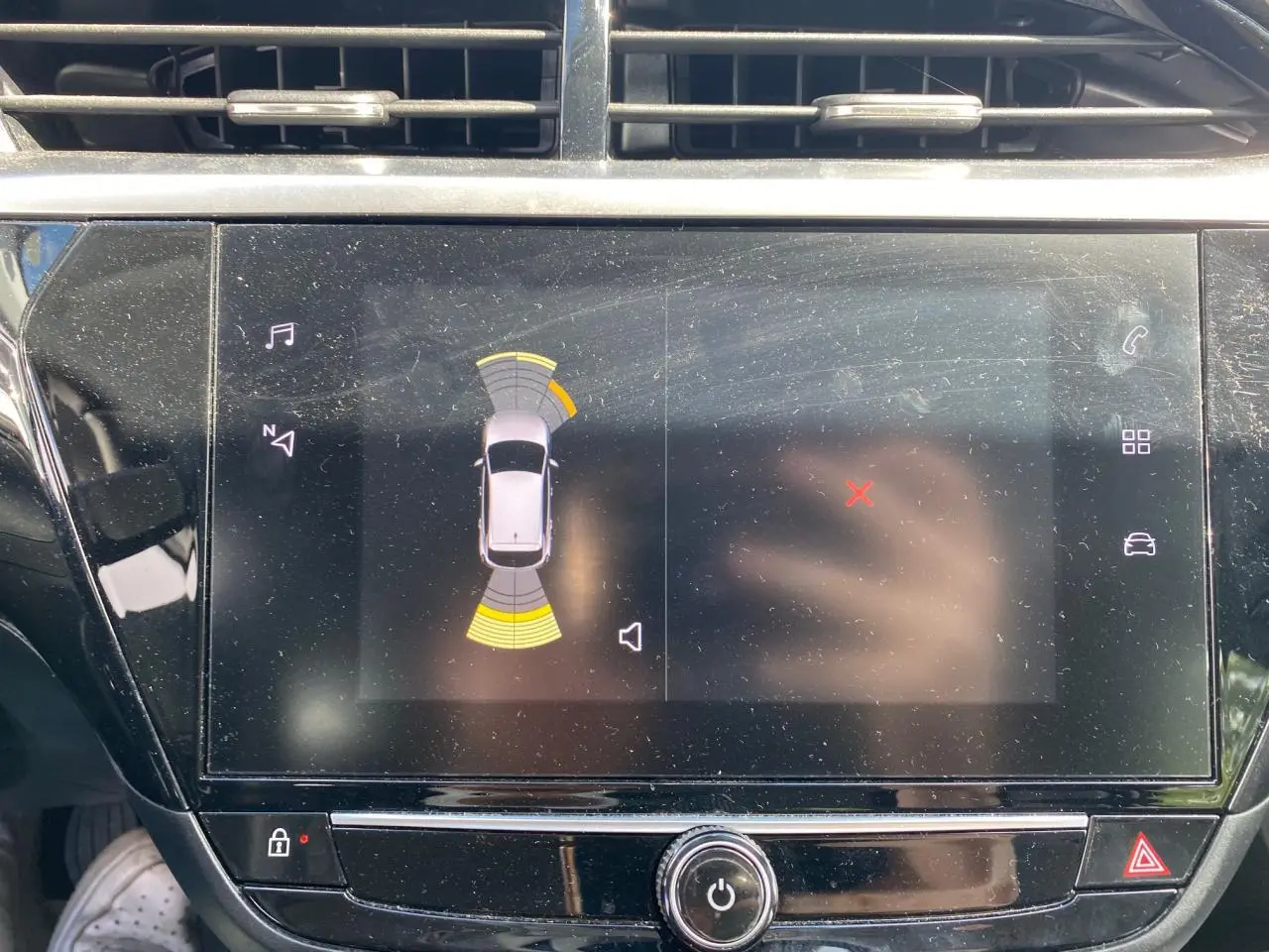 Écran tactile central de l'Opel Corsa bleu nautique 2021 affichant l'aide au stationnement avec capteurs actifs.