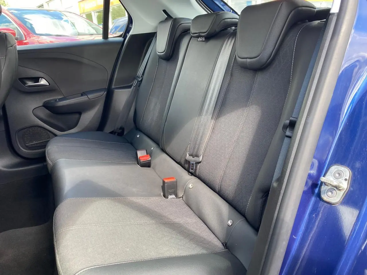 Vue côté droit de la banquette arrière noire de l'Opel Corsa bleu nautique avec ceinture et appuie-têtes visibles.