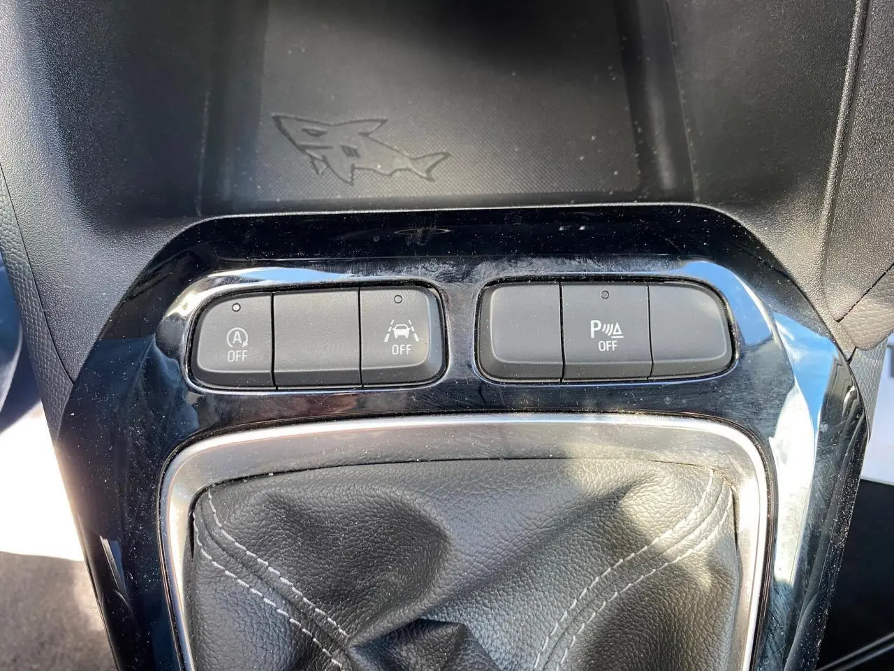 Gros plan sur la console centrale noire de l'Opel Corsa 1.2i Turbo 2021 avec boutons de contrôle et soufflet de levier de vitesse en cuir.