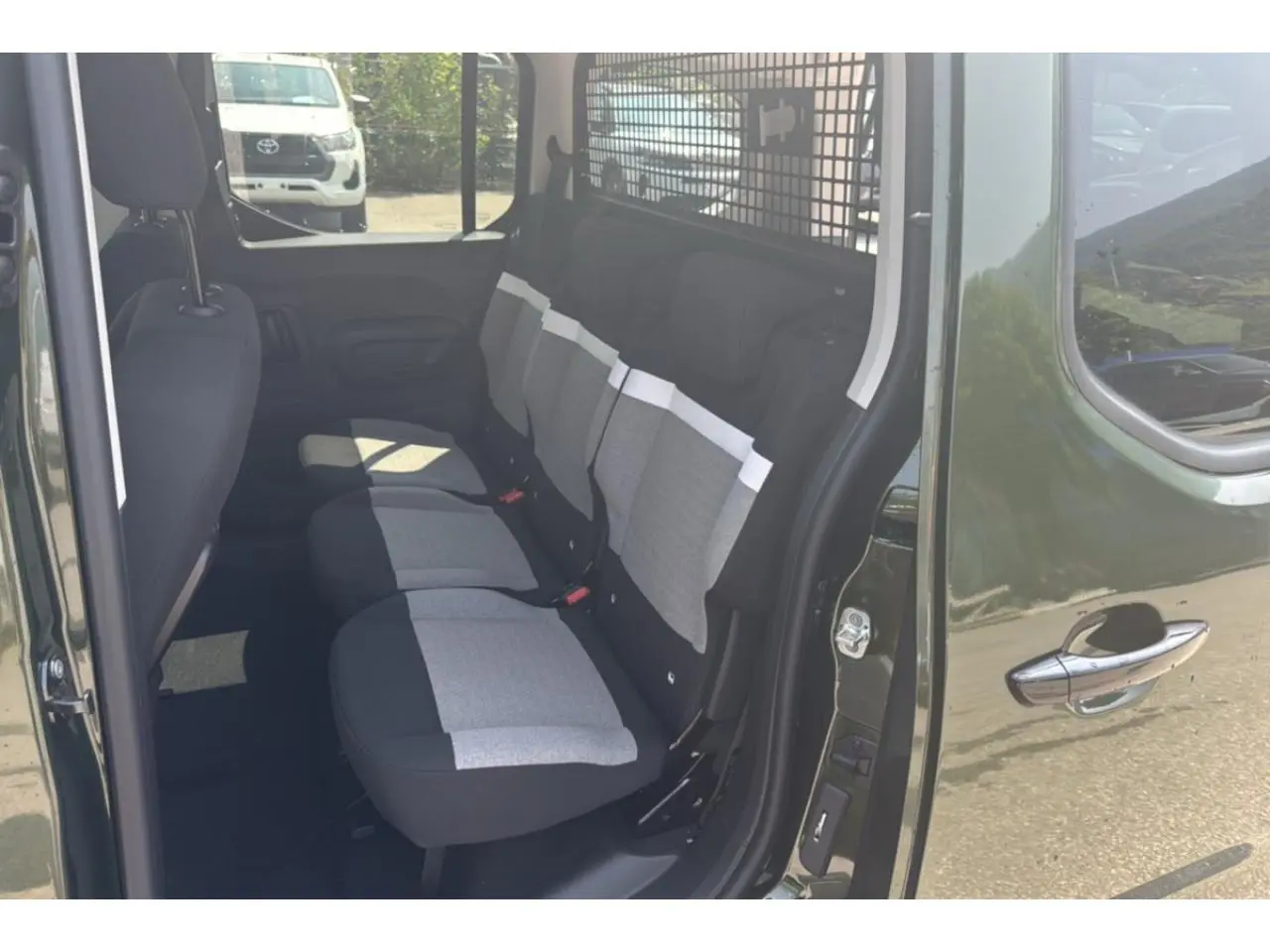 Vue intérieure côté droit du Citroën Berlingo vert Sirka, montrant les sièges arrière en tissu bicolore gris et noir.