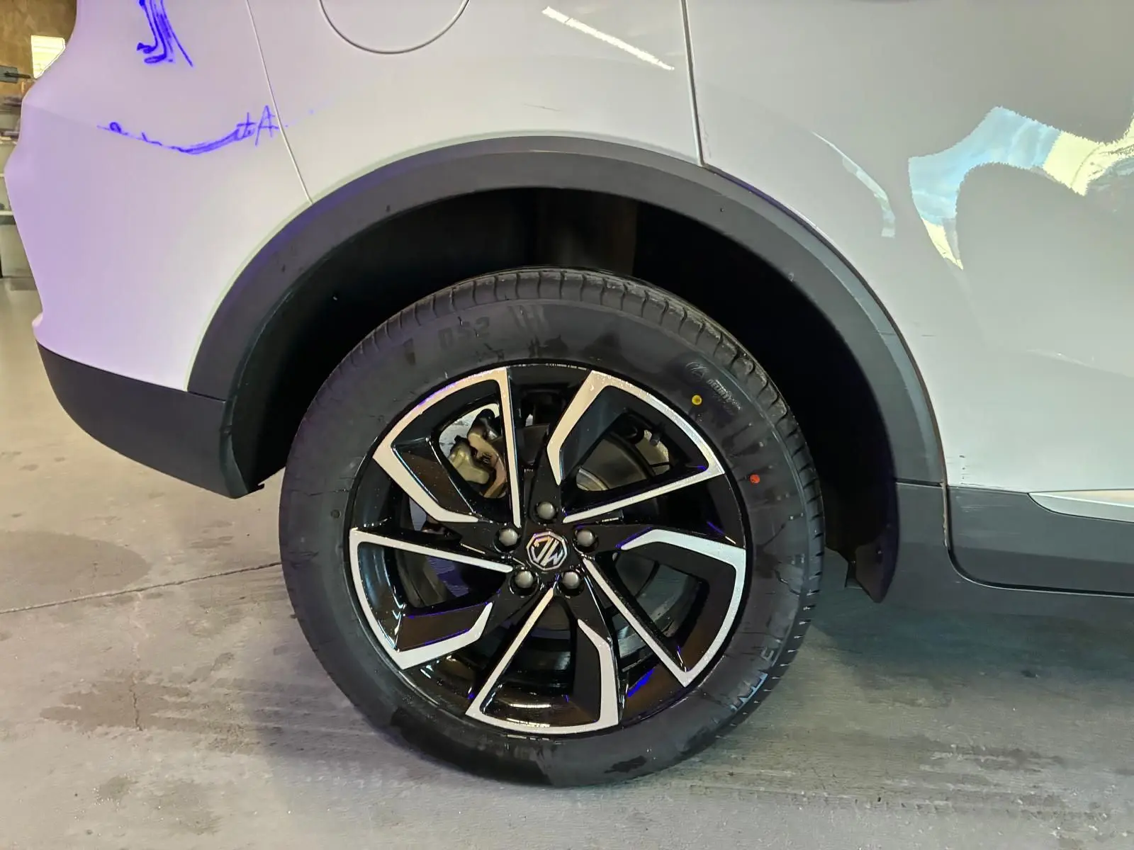 Gros plan sur la roue arrière droite du MG ZS blanc, mettant en valeur la jante noire et argentée au design moderne.