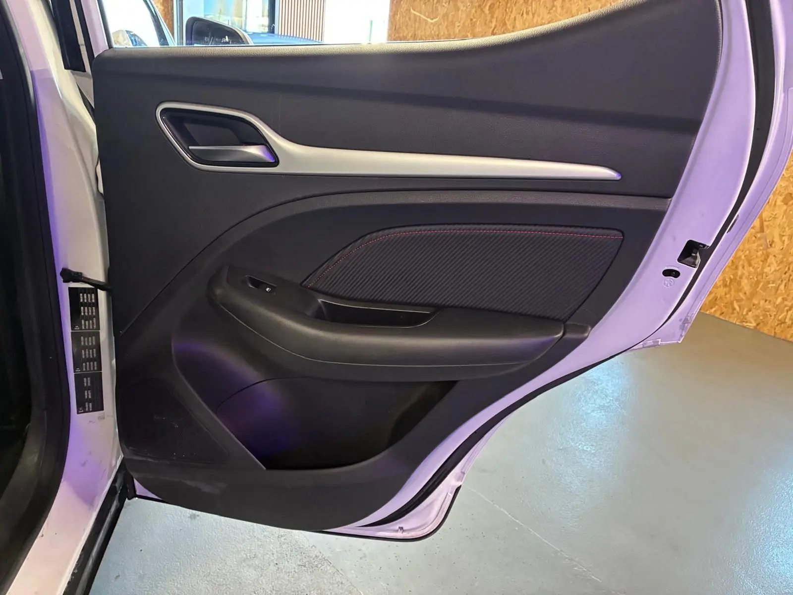 Vue intérieure de la porte arrière droite blanche du MG ZS 2022 avec garniture noire et surpiqûres rouges.