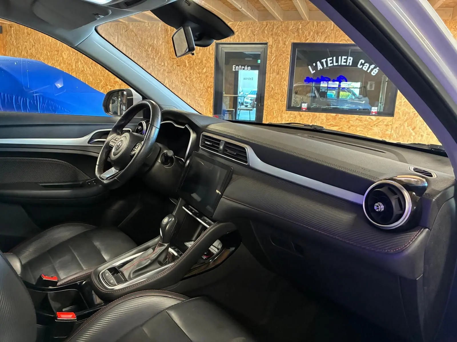 Vue intérieure côté conducteur du MG ZS 1.0 TGDI 111 BVA Luxury 2022 avec sellerie cuir noire et tableau de bord moderne.