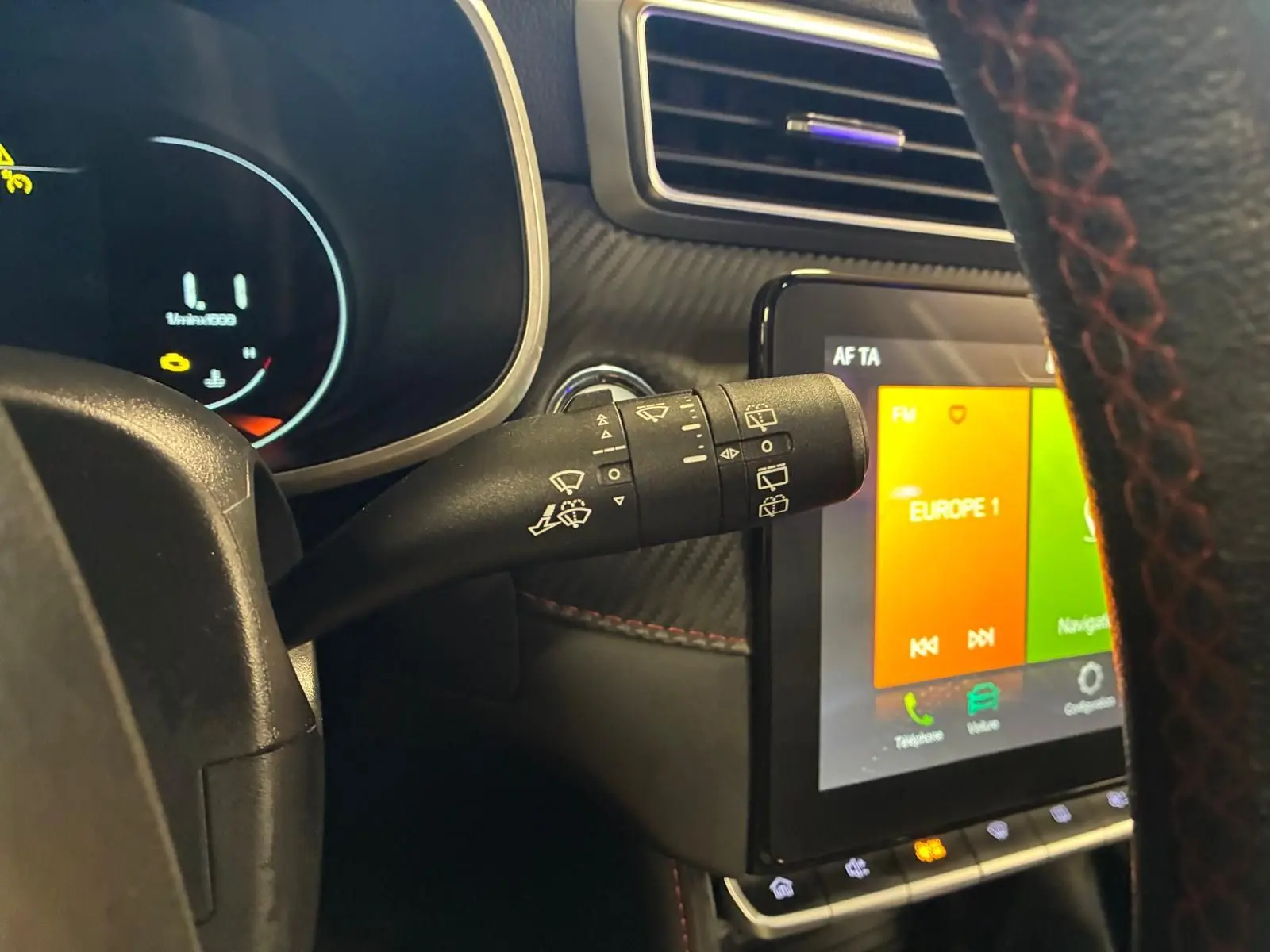 Gros plan sur la commande d’essuie-glace à gauche du volant dans l’habitacle noir du MG ZS blanc, avec écran tactile visible.