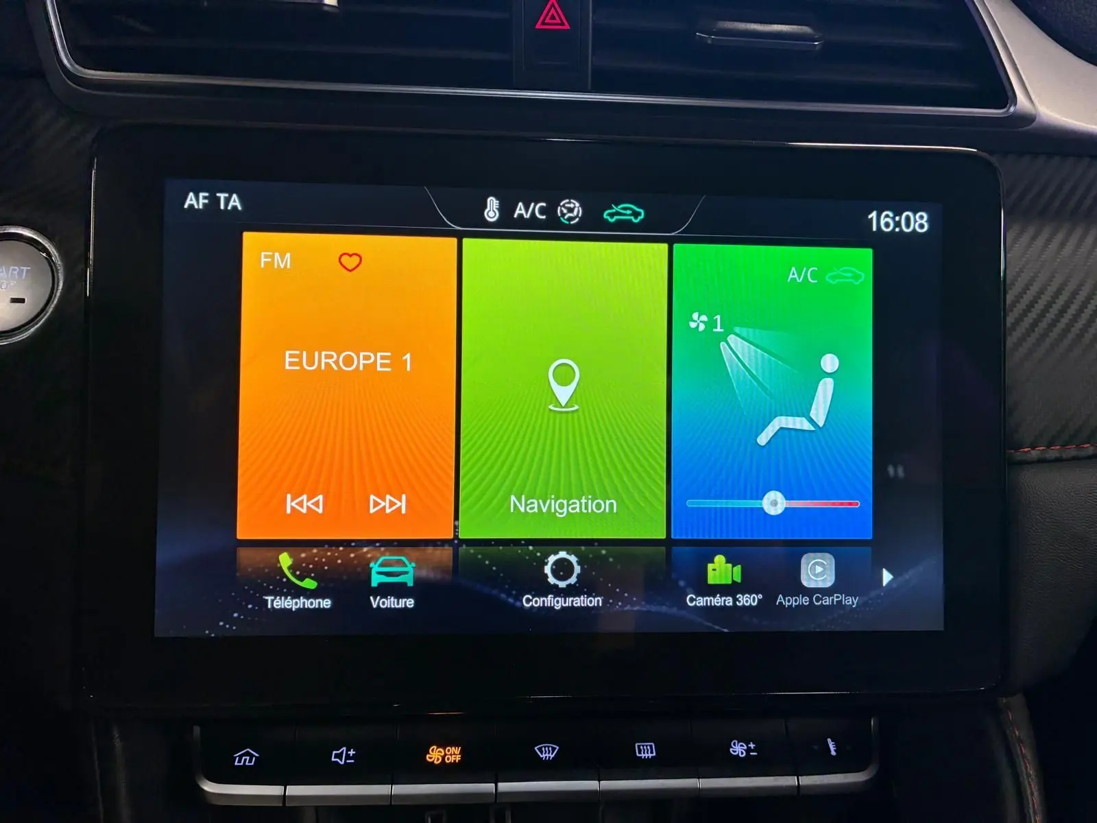 Écran tactile central de la MG ZS 2022, affichant radio, navigation et commandes climatisation, intérieur noir avec détails rouges.