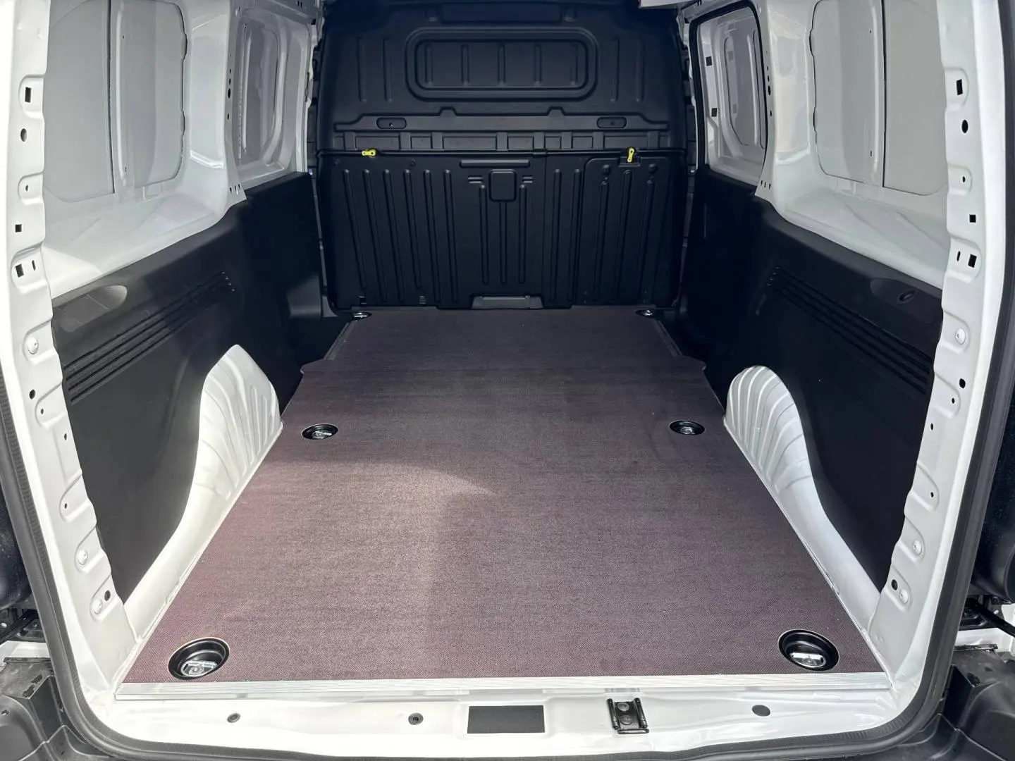 Vue intérieure arrière du Citroën Berlingo Fourgon XL blanc Icy, montrant l’espace de chargement vide et protégé.
