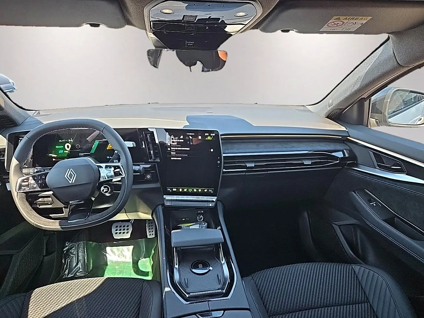 Vue avant de l’intérieur noir du Renault Austral blanc nacré, avec écran tactile vertical et volant multifonction.