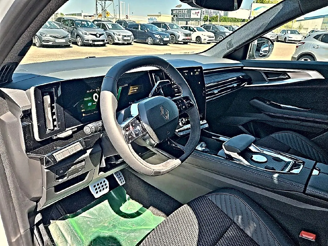 Vue intérieure côté conducteur du Renault Austral blanc nacré, mettant en valeur le volant multifonction et l’écran tactile central.