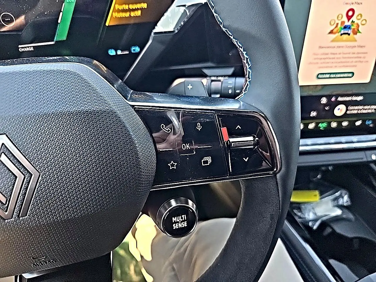 Gros plan sur le volant noir du Renault Austral blanc nacré, avec commandes multifonctions et bouton Multi Sense visible.