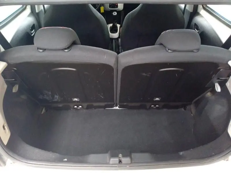 Vue depuis le coffre du Citroën C1 blanc 2018, montrant la banquette arrière 50/50 et l'espace de chargement noir.