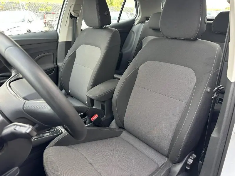 Vue intérieure des sièges avant en tissu gris Kota Grey de la Skoda Fabia 2024, avec accoudoir central et volant cuir multifonction.