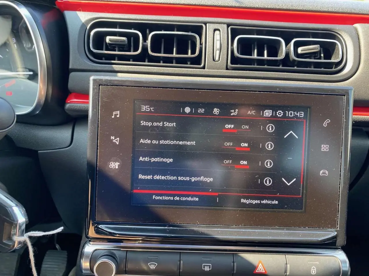Vue rapprochée du tableau de bord de la Citroën C3 orange, mettant en valeur l'écran tactile central avec réglages activés.